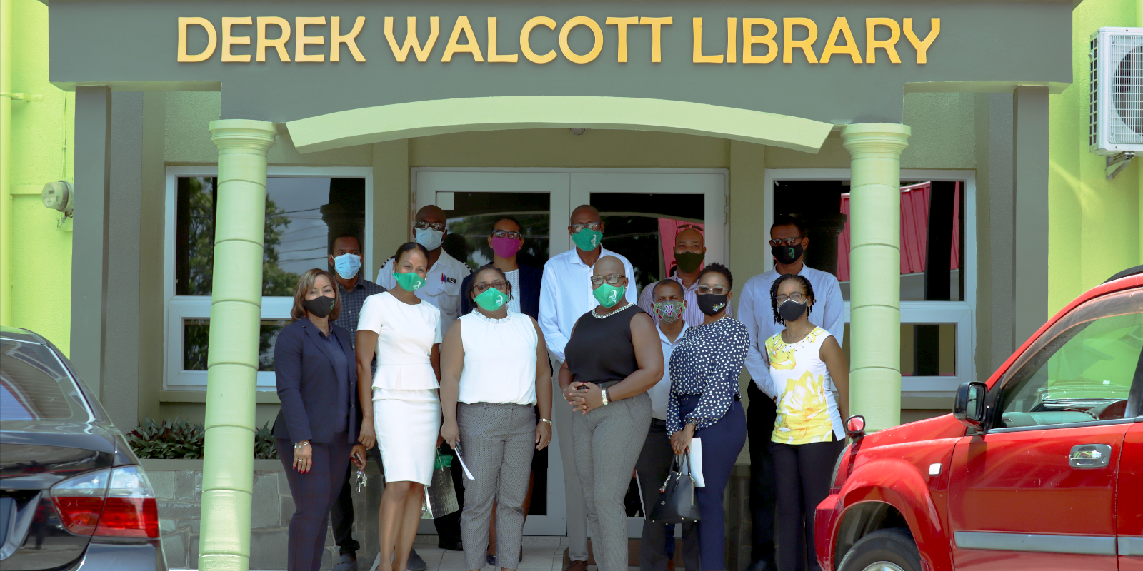 The Honourable Dr. Gale Rigobert poses with members of staff before the newly opened Derek Walcott Library.